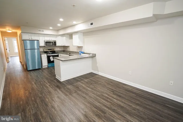a kitchen with stainless steel appliances wooden floor and a refrigerator