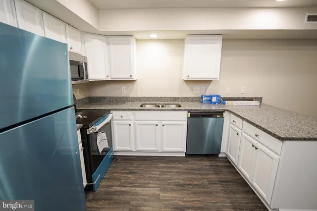 a kitchen with granite countertop a sink stove and refrigerator