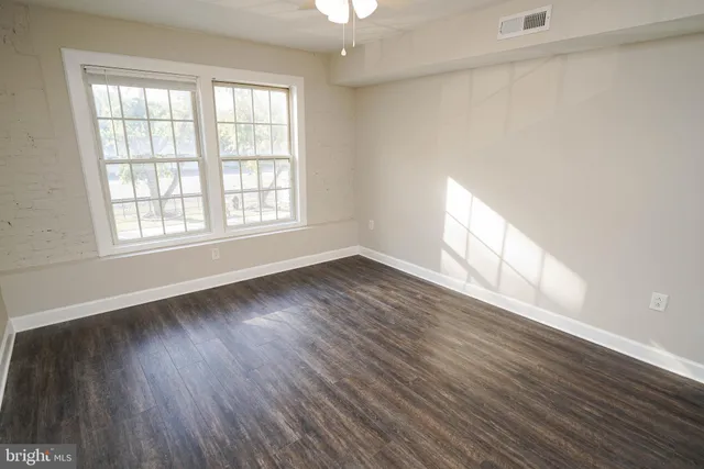 an empty room with wooden floor and windows