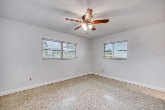 an empty room with windows and ceiling fan