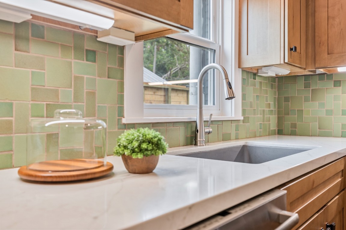 1104 Walton Street Houston, TX 77009 - Photo 10 of 27 A close-up of the gooseneck faucet and quartz countertops, highlighted by a handcrafted tile backsplash, showcases the kitchen's attention to detail.