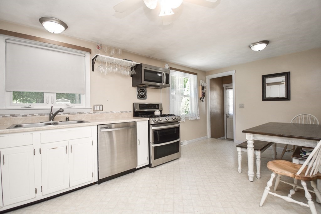 128 Tioga Street Springfield, MA 01128 - Photo 8 of 33 a kitchen with white cabinets and chairs
