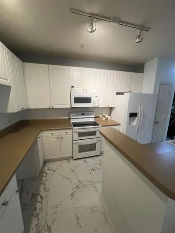 a kitchen with granite countertop a refrigerator and a stove top oven