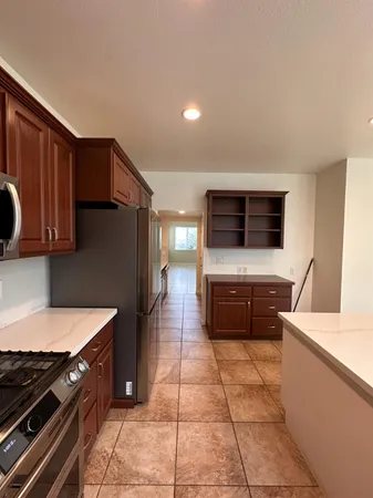 a kitchen with kitchen island granite countertop a refrigerator stove top oven and sink