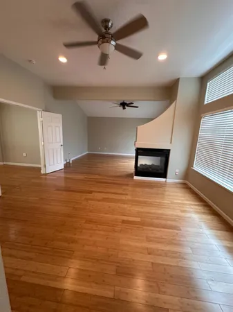 an empty room with wooden floor and windows