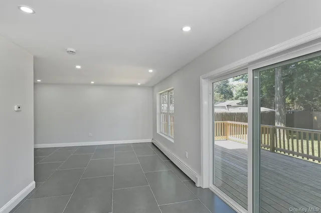 a view of a refrigerator in kitchen and an empty room with wooden floor windows