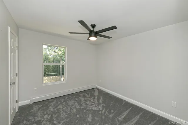an empty room with a window and a fan