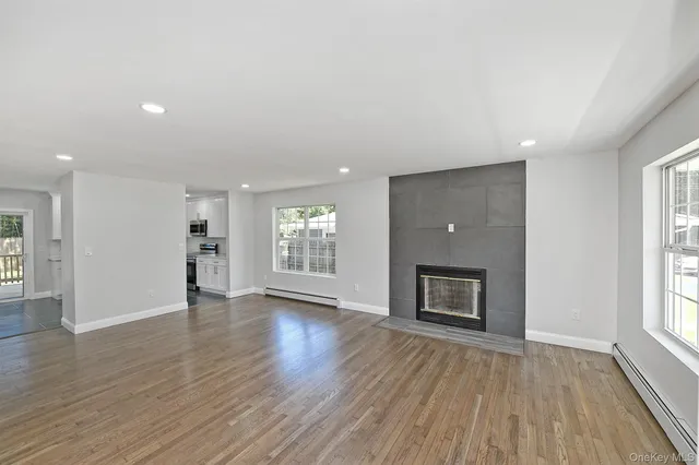 an empty room with wooden floor fireplace and windows