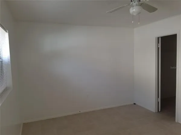 an empty room with a window and a fan