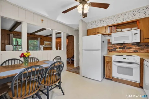 a kitchen with stainless steel appliances granite countertop a refrigerator a stove a sink a dining table and chairs with wooden floor