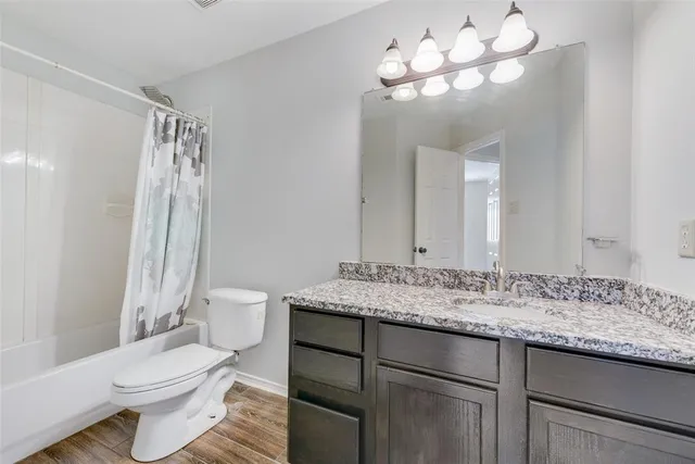 a bathroom with a granite countertop sink toilet and a mirror