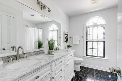 a spacious bathroom with a granite countertop sink a large mirror a toilet and a window