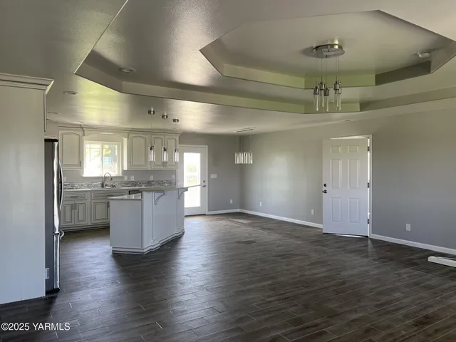 an empty room with wooden floor and kitchen view