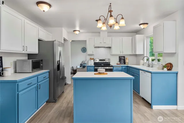 a kitchen with kitchen island granite countertop a sink a stove a refrigerator cabinets and a dining table