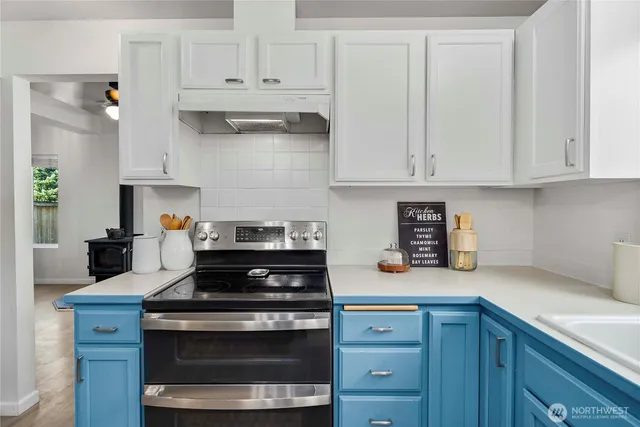 a kitchen with stainless steel appliances granite countertop a stove and white cabinets