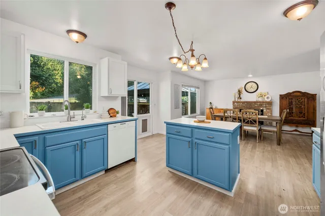 a open kitchen with stainless steel appliances granite countertop a stove a refrigerator a sink dishwasher with a dining table and chairs with wooden floor