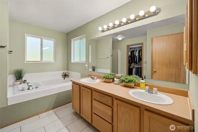 a bathroom with a sink double vanity granite tub and a mirror