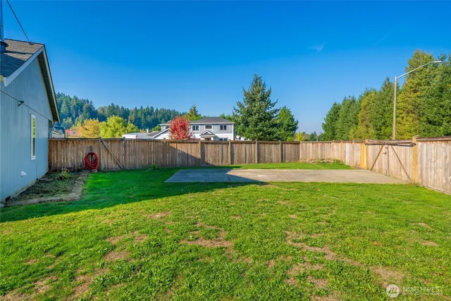 a view of a yard with swimming pool and wooden fence