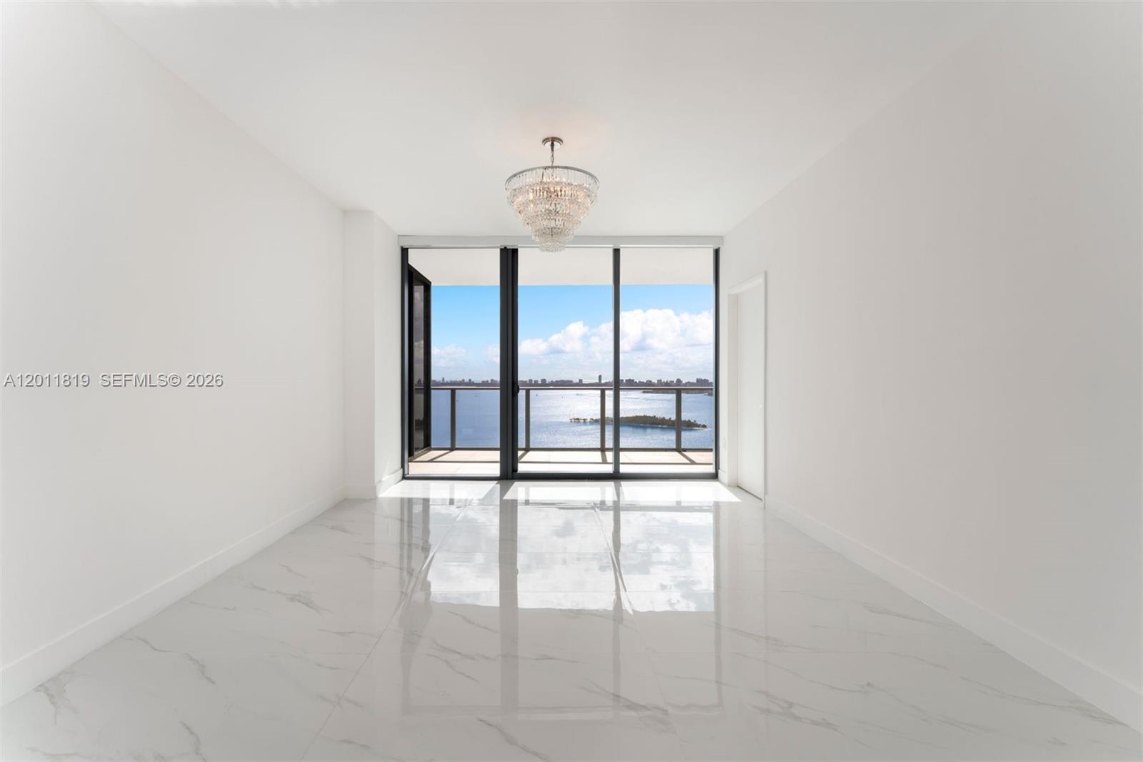 700 Northeast 24th Street, Unit 2504 Miami, FL 33137 - Photo 18 of 52 Serene primary suite offering unobstructed water views, direct terrace access, oversized walk-in closets, and floor-to-ceiling windows for a true 'mansion in the sky' feel.