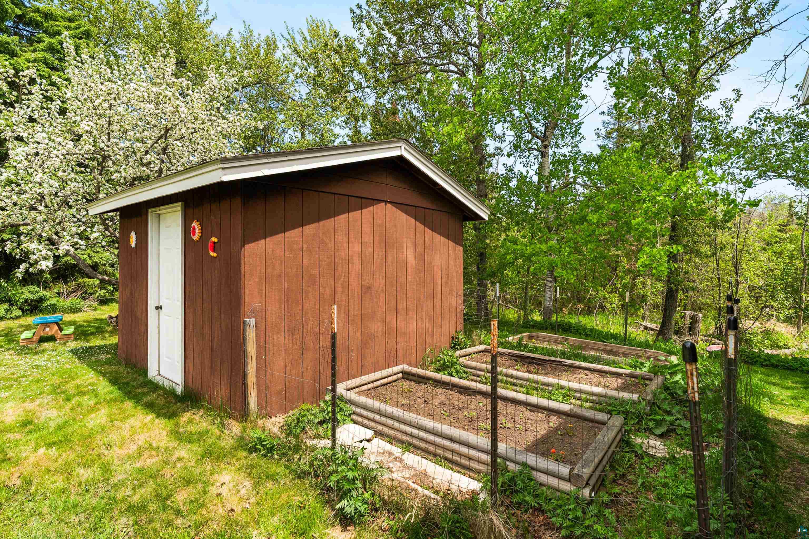 4808 Midway Road Duluth, MN 55811 - Photo 54 of 57 Brown wood-sided shed with a white door, positioned on a grassy area
