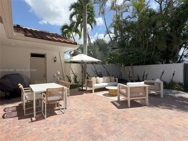 a view of a patio with a dining table and chairs under an umbrella