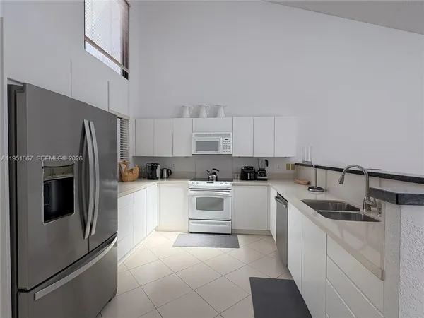 a kitchen with granite countertop white cabinets and stainless steel appliances