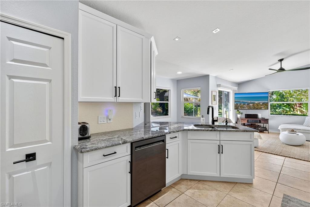 1081 9th Street Southwest Naples, FL 34117 - Photo 12 of 40 Kitchen with a peninsula, white cabinetry, dark stone countertops, dishwashing machine, and light tile patterned floors