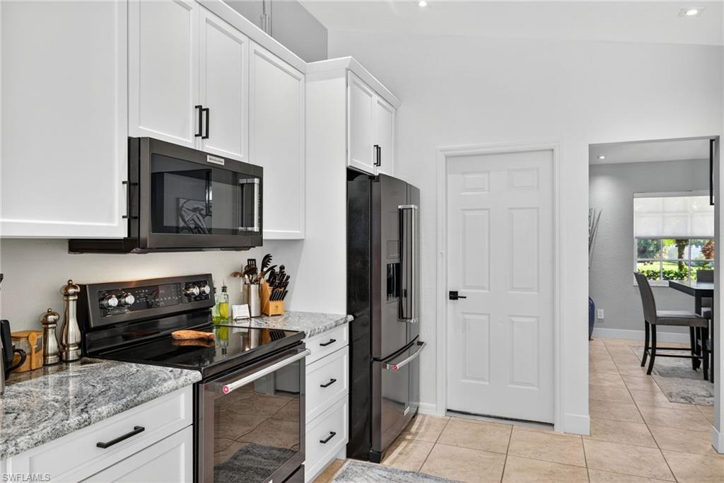 1081 9th Street Southwest Naples, FL 34117 - Photo 13 of 40 Kitchen featuring electric stove, high end refrigerator, white cabinetry, light stone countertops, and recessed lighting