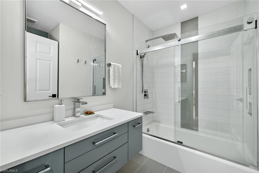 1081 9th Street Southwest Naples, FL 34117 - Photo 14 of 40 Full bathroom with vanity, enclosed tub / shower combo, and dark tile patterned floors