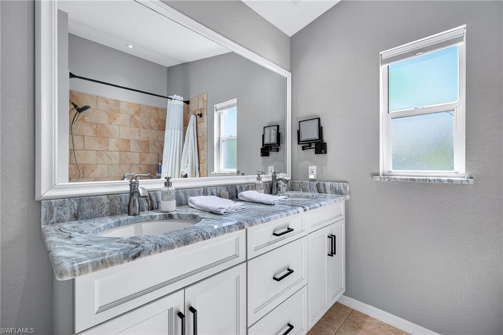 1081 9th Street Southwest Naples, FL 34117 - Photo 20 of 40 Full bathroom with double vanity, tiled shower, light tile patterned floors, and a textured wall