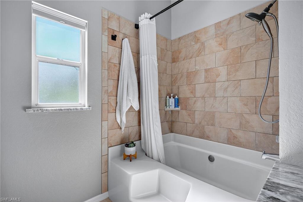 1081 9th Street Southwest Naples, FL 34117 - Photo 21 of 40 Full bath featuring shower / bath combo with shower curtain and a textured wall