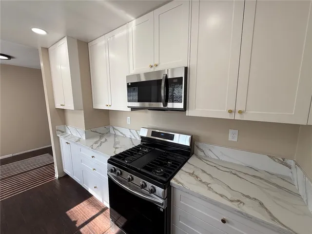 a kitchen with stainless steel appliances granite countertop a stove a microwave and a white cabinets