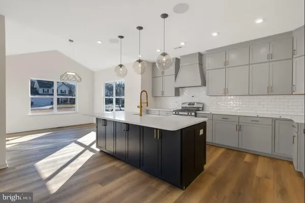 a kitchen with stainless steel appliances granite countertop a sink a stove and a wooden floors