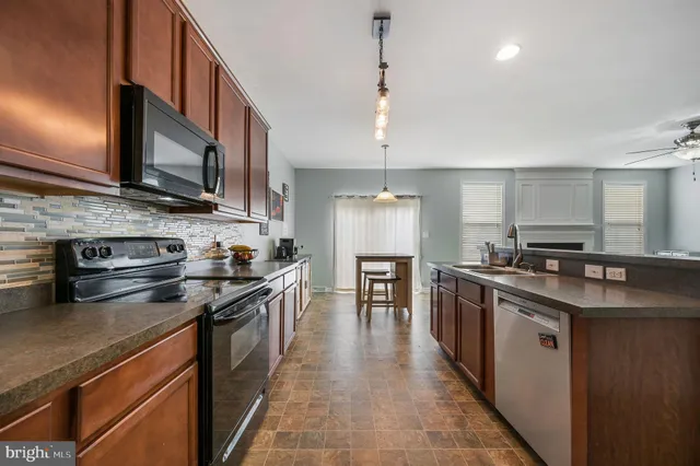 a kitchen with stainless steel appliances granite countertop a stove a sink dishwasher a refrigerator and a oven with wooden floor