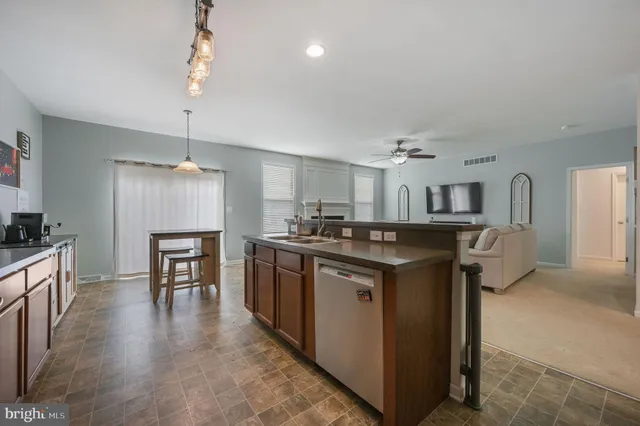 a kitchen with stainless steel appliances granite countertop a refrigerator a sink dishwasher a stove and a dining table with wooden floor