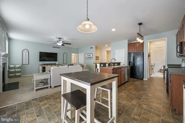 a kitchen with stainless steel appliances granite countertop a stove top oven a refrigerator a sink dishwasher a dining table and chairs with wooden floor