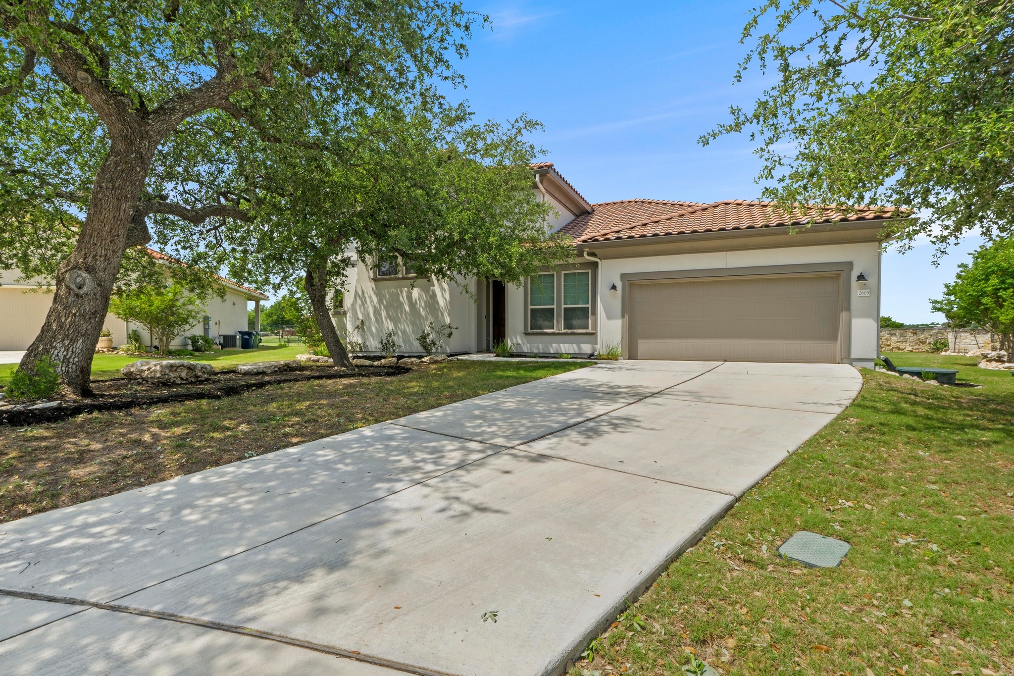 2609 Antalya Loop Leander, TX 78641 - Photo 40 of 40 Mediterranean-style house with a front lawn, driveway, a tiled roof, an attached garage, and stucco siding.