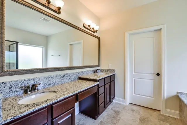 a bathroom with a granite countertop sink and a mirror