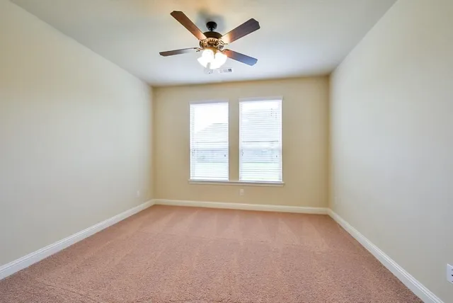 an empty room with a window and a fan