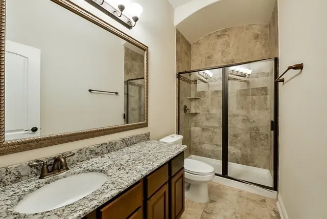 a bathroom with a granite countertop sink toilet and shower