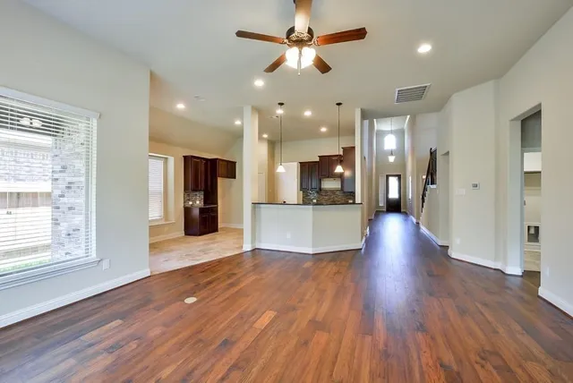 a view of a big room with wooden floor and a kitchen