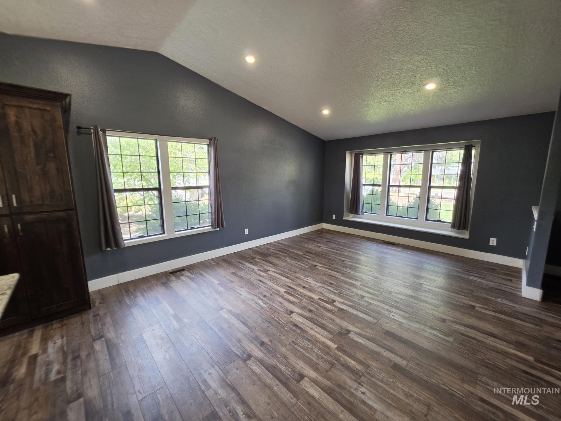 3201 South Riva Ridge Way Boise City, ID 83709 - Photo 2 of 29 Vaulted ceiling with recessed lighting, wood-finish flooring, and a large window with white trim
