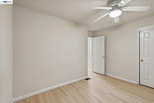 an empty room with wooden floor fan and windows