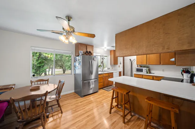 a kitchen with stainless steel appliances granite countertop a stove top oven a sink dishwasher and a refrigerator with wooden floor