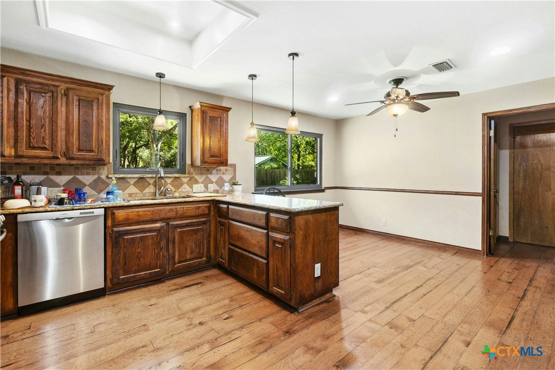 3502 Apache Forest Drive Austin, TX 78739 - Photo 18 of 34 a kitchen with stainless steel appliances granite countertop a refrigerator a sink dishwasher a stove and white countertops with wooden floor
