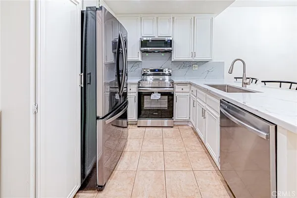 a kitchen with stainless steel appliances granite countertop a refrigerator a sink a stove a dining table and chairs