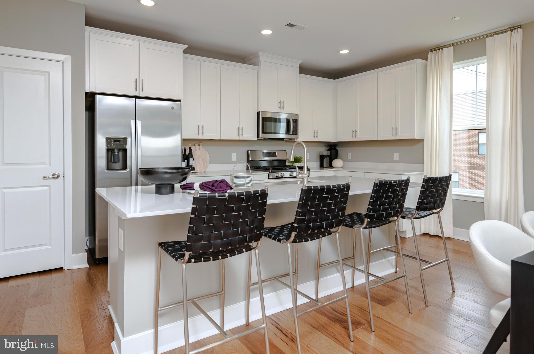 a kitchen with stainless steel appliances kitchen island granite countertop a refrigerator a stove top oven a sink a dining table and chairs