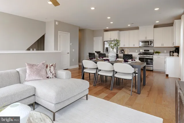a living room with furniture and a dining table with wooden floor