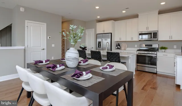 a kitchen that has stainless steel appliances stove refrigerator dining table and chairs