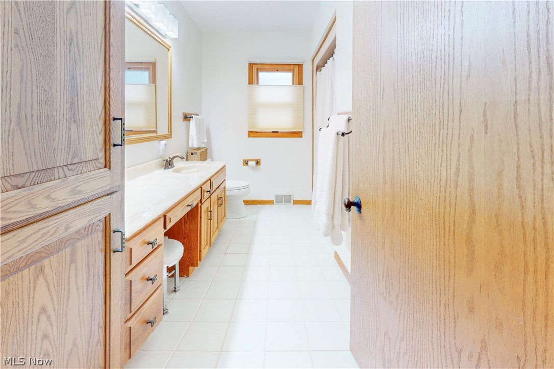 86532 North Bay Road Scio, OH 43988 - Photo 38 of 48 Bathroom featuring a spacious wood-finish vanity with an integrated sink and ample counter space, white tile flooring, and a built-in linen cabinet